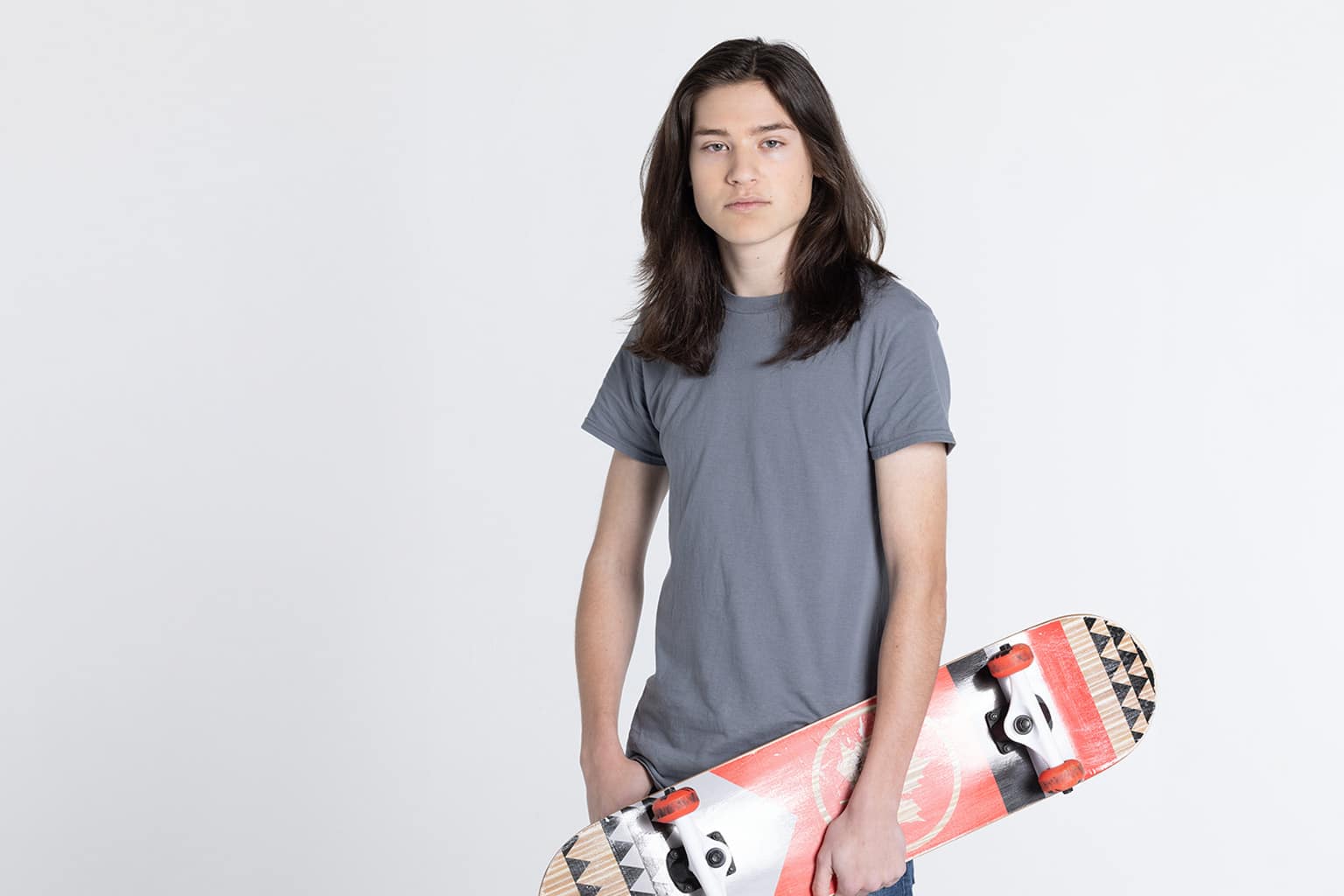 Teen male looking at the camera and holding a skateboard
