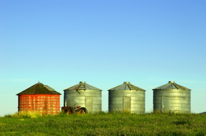 Three new and one old grain silo, plus a tractor. Taken in rural Montana.