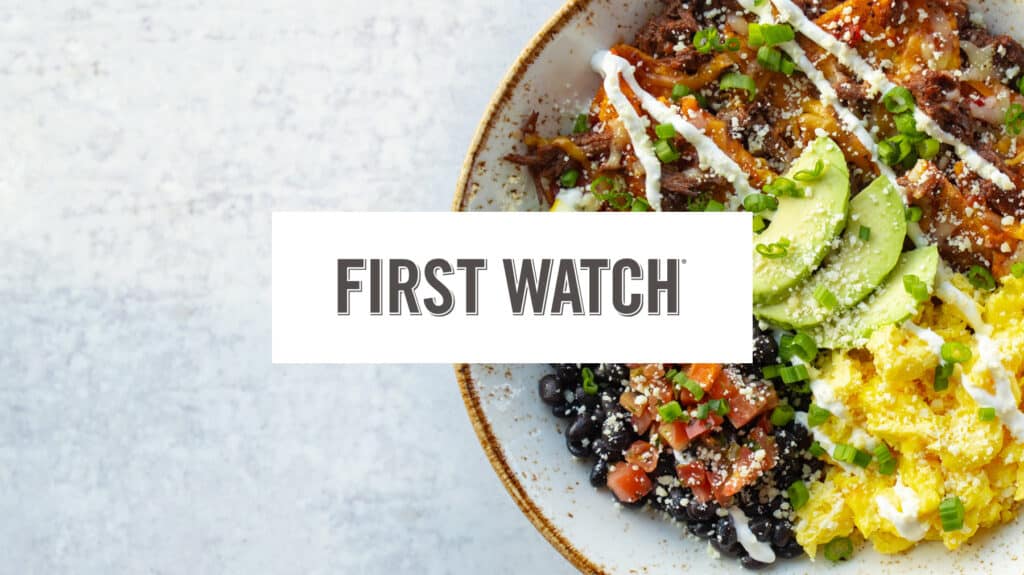 A colorful breakfast bowl with avocado, eggs, beans, and salsa prepared by First Watch.