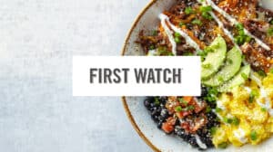 A colorful breakfast bowl with avocado, eggs, beans, and salsa prepared by First Watch.