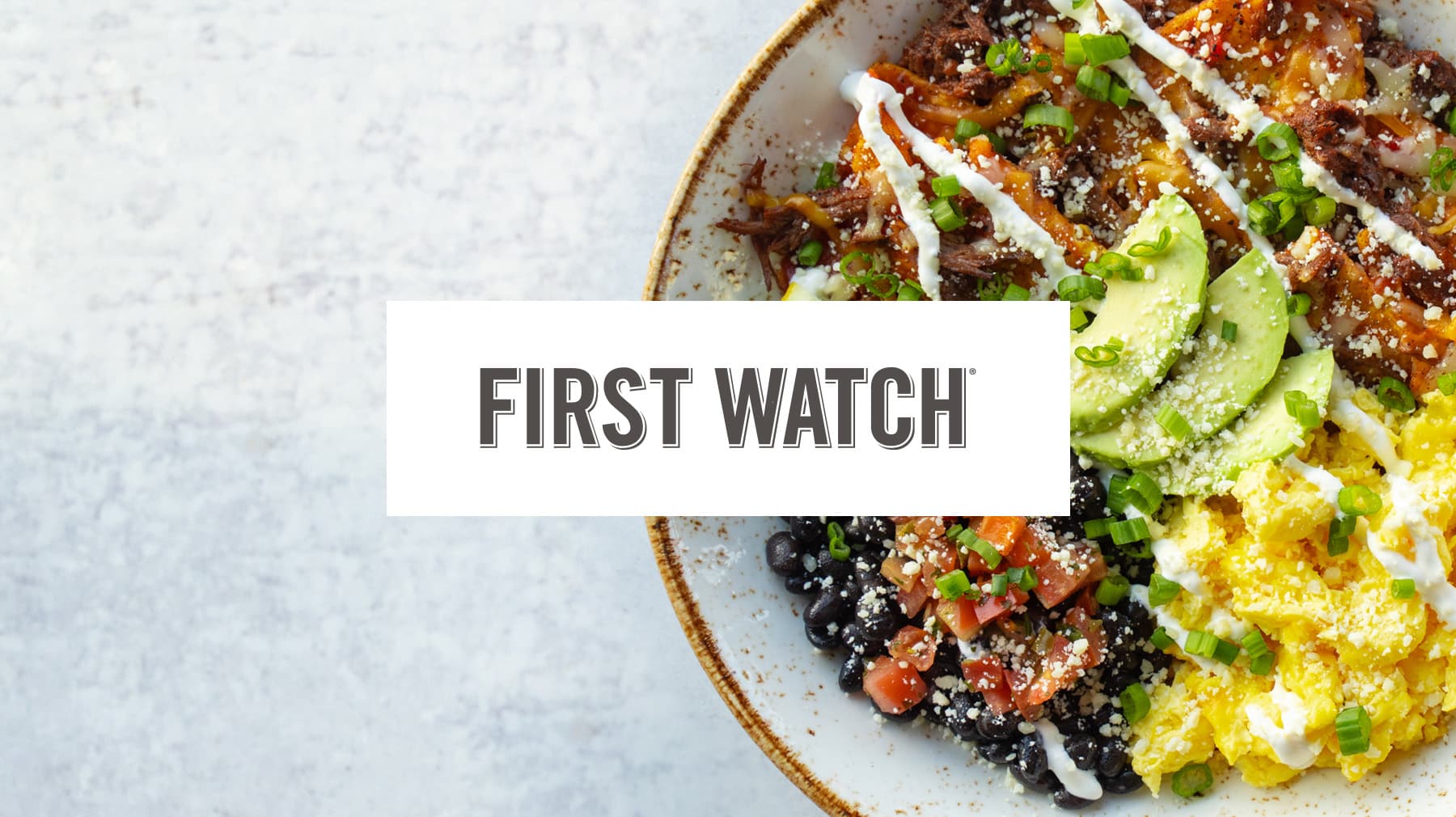 A colorful breakfast bowl with avocado, eggs, beans, and salsa prepared by First Watch.