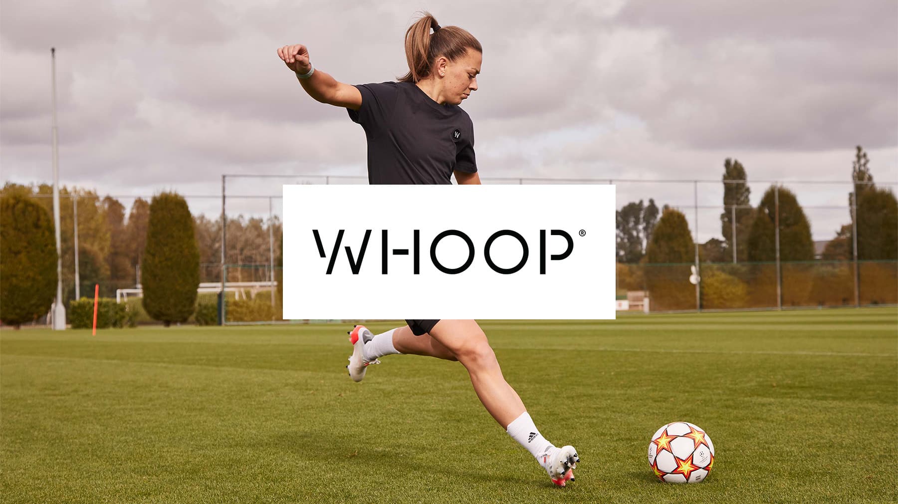 A female soccer player kicking a ball on a grass field during practice.